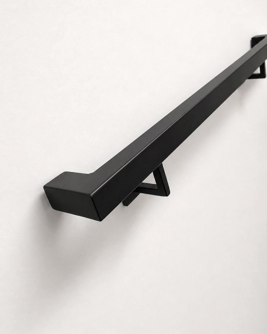 1-1/2 inch square matte black steel handrail mounted on a wall, showing the mitred return end and wall bracket