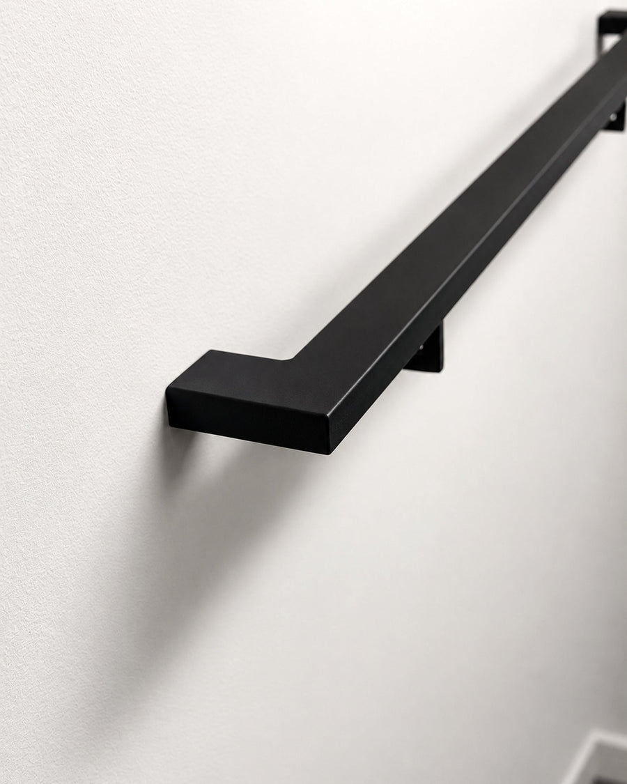2 inch by 1 inch matte black steel handrail mounted on a wall, showing the mitred return end and wall bracket