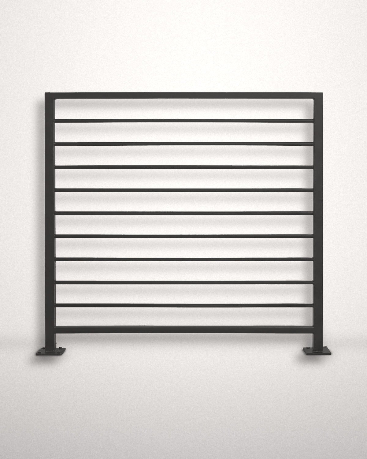Horizon horizontal bar railing panel in matte black powder coated steel standing against a plain wall — welded guardrail with evenly spaced horizontal bars and bolt-down base plates, custom made to size in New Jersey