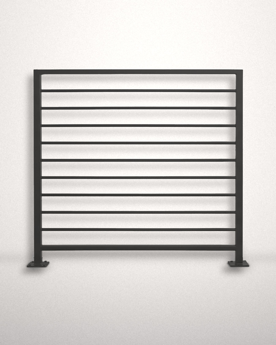Horizon horizontal bar railing panel in matte black powder coated steel standing against a plain wall — welded guardrail with evenly spaced horizontal bars and bolt-down base plates, custom made to size in New Jersey