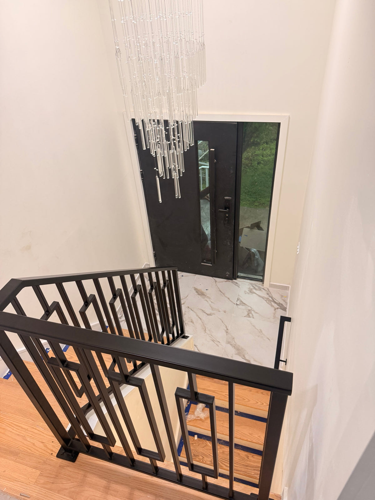 Keystone framed railing installed on a landing above a two storey foyer, matte black powder coated steel with the floating frames, looking down to the front door