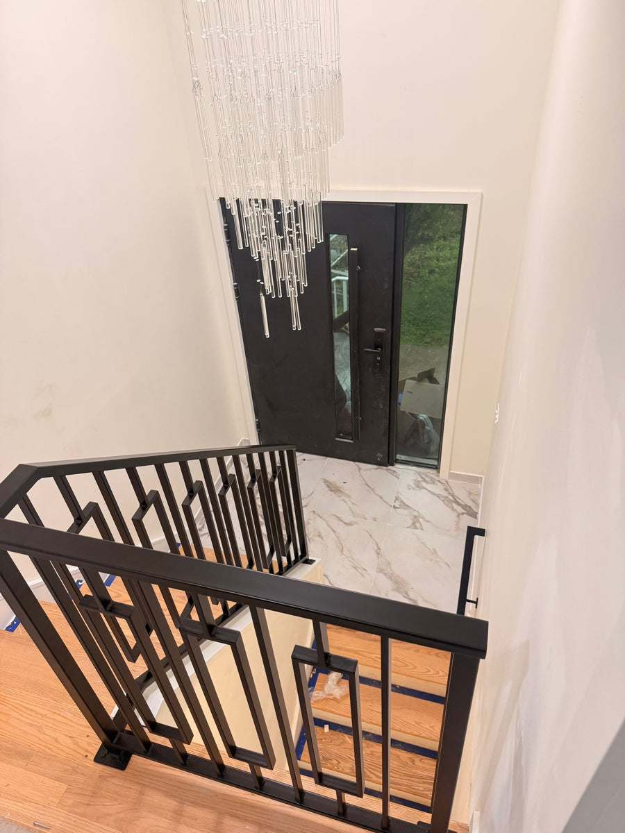 Keystone framed railing installed on a landing above a two storey foyer, matte black powder coated steel with the floating frames, looking down to the front door