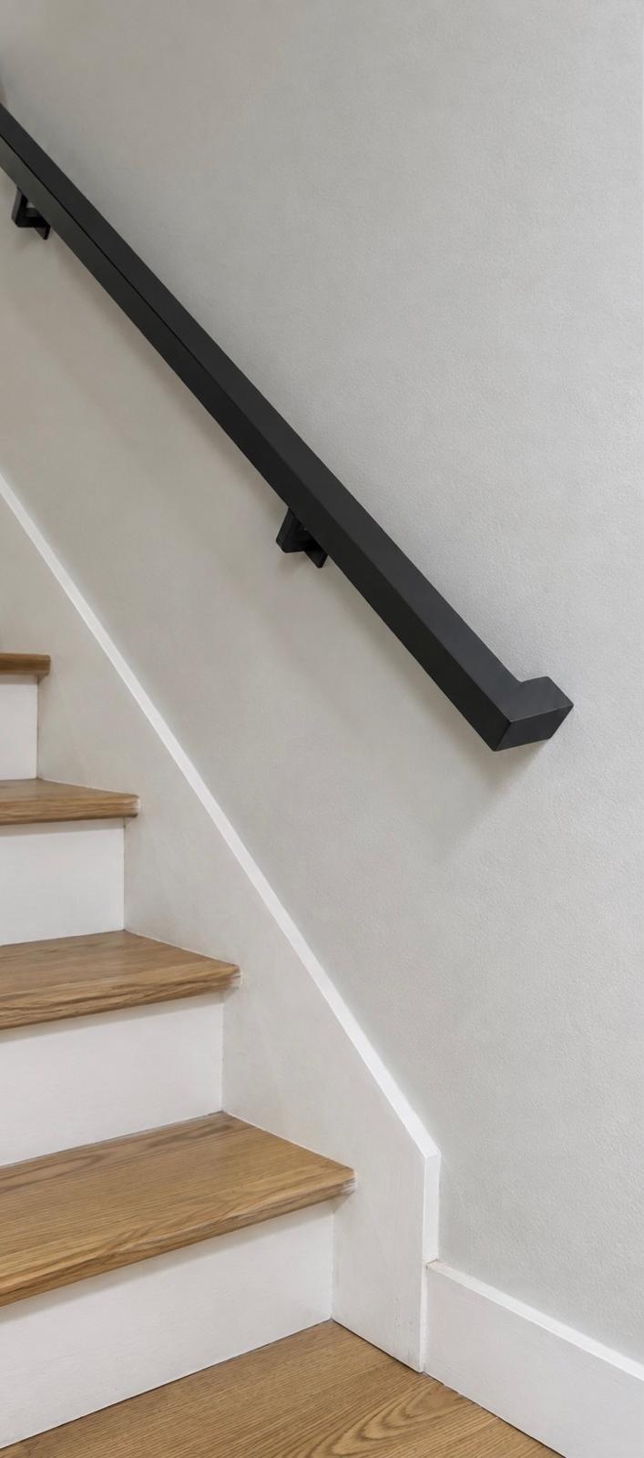 1-1/2 inch square matte black steel handrail mounted on a stair wall, mitred return into the wall